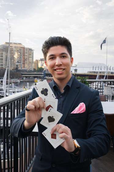 TDog holding a fan of cards on a harbourside terrace