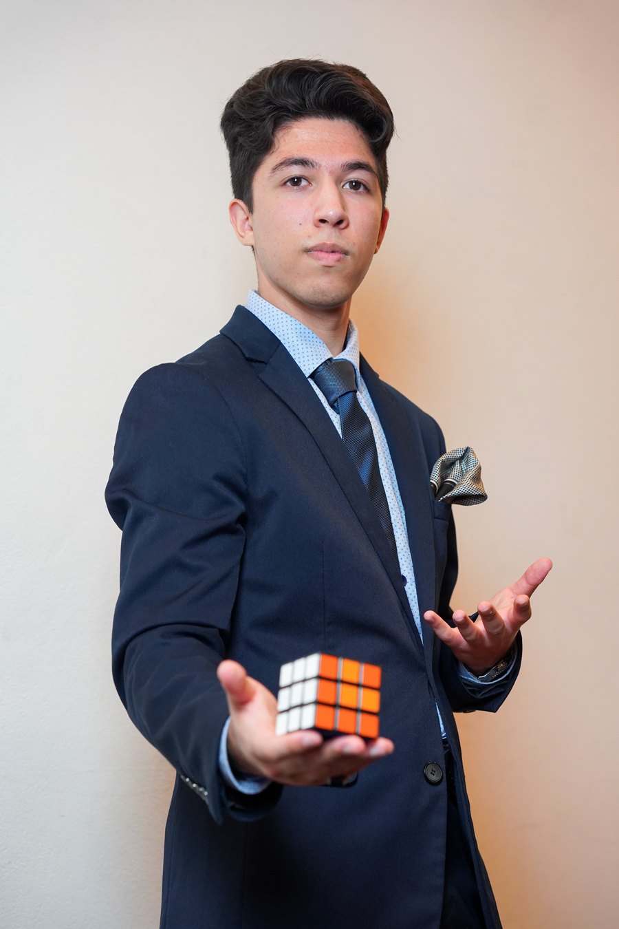 TDog in a navy suit presenting a Rubik&rsquo;s Cube