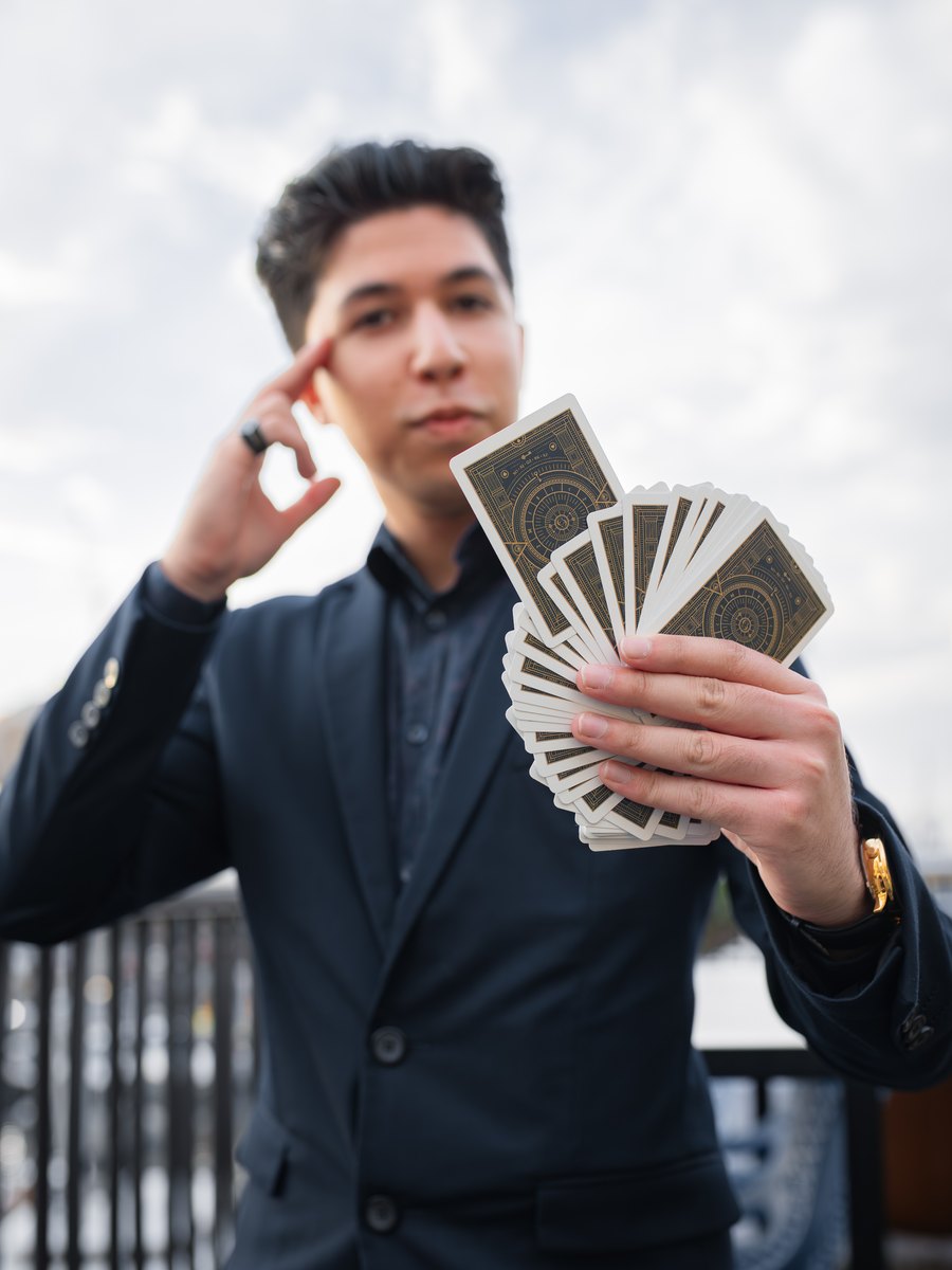 TDog in a dark suit holding playing cards